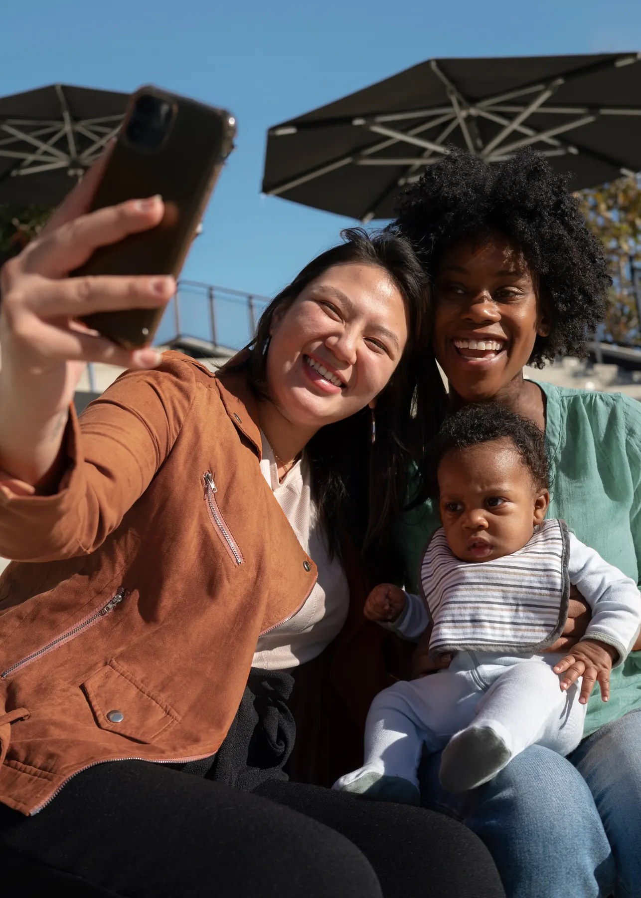 Two women taking a selfie with a baby in the sunshine