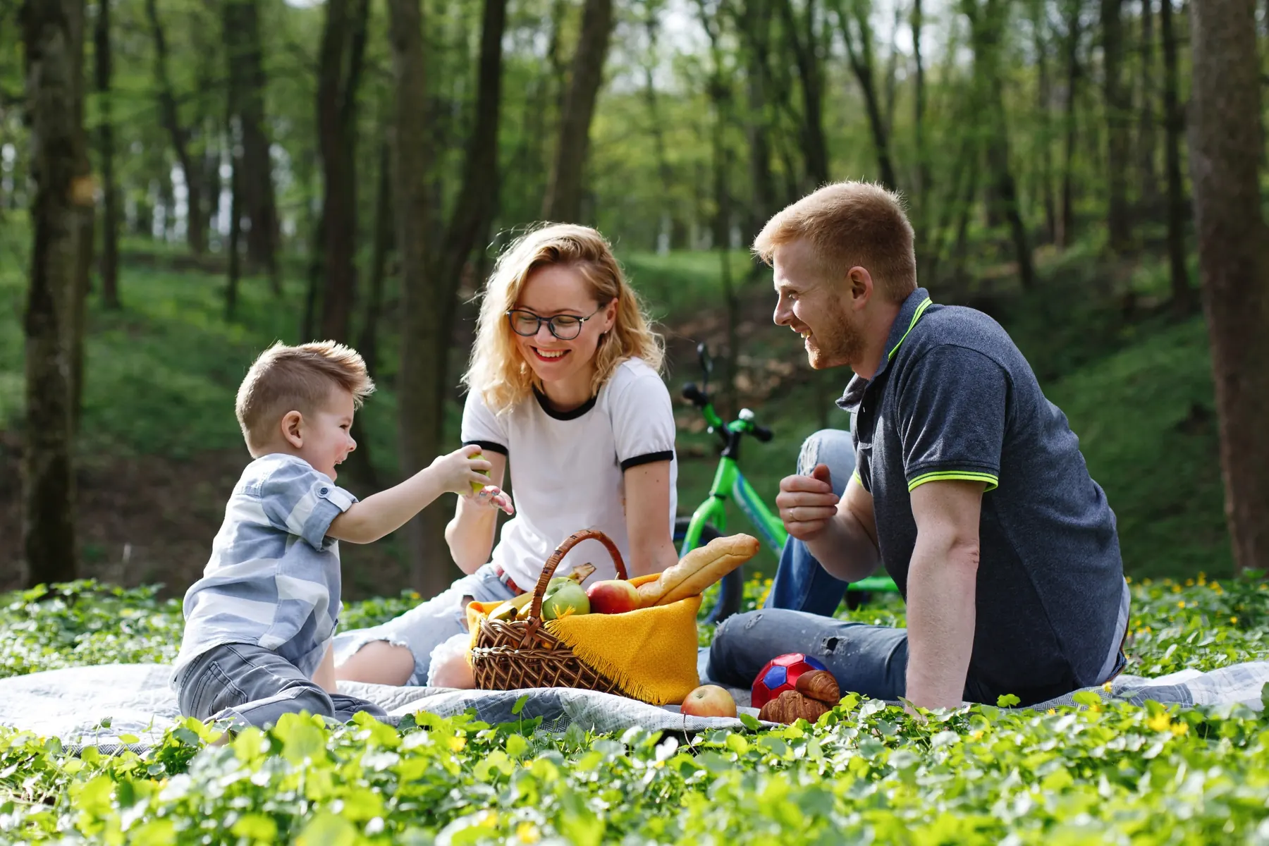 A family laughing together at a picnic in the park