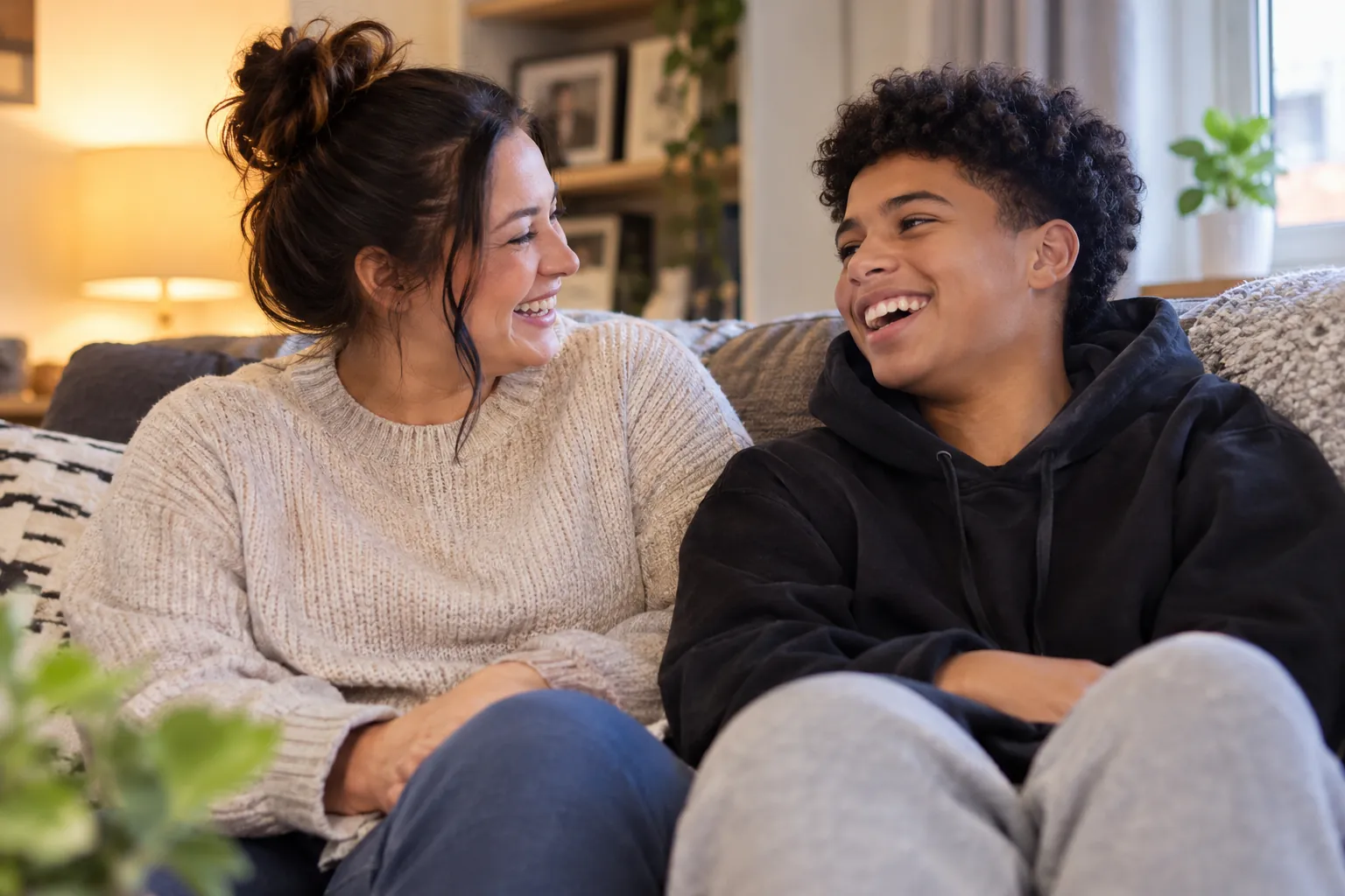 A foster carer and a teenage boy sharing a laugh on the sofa