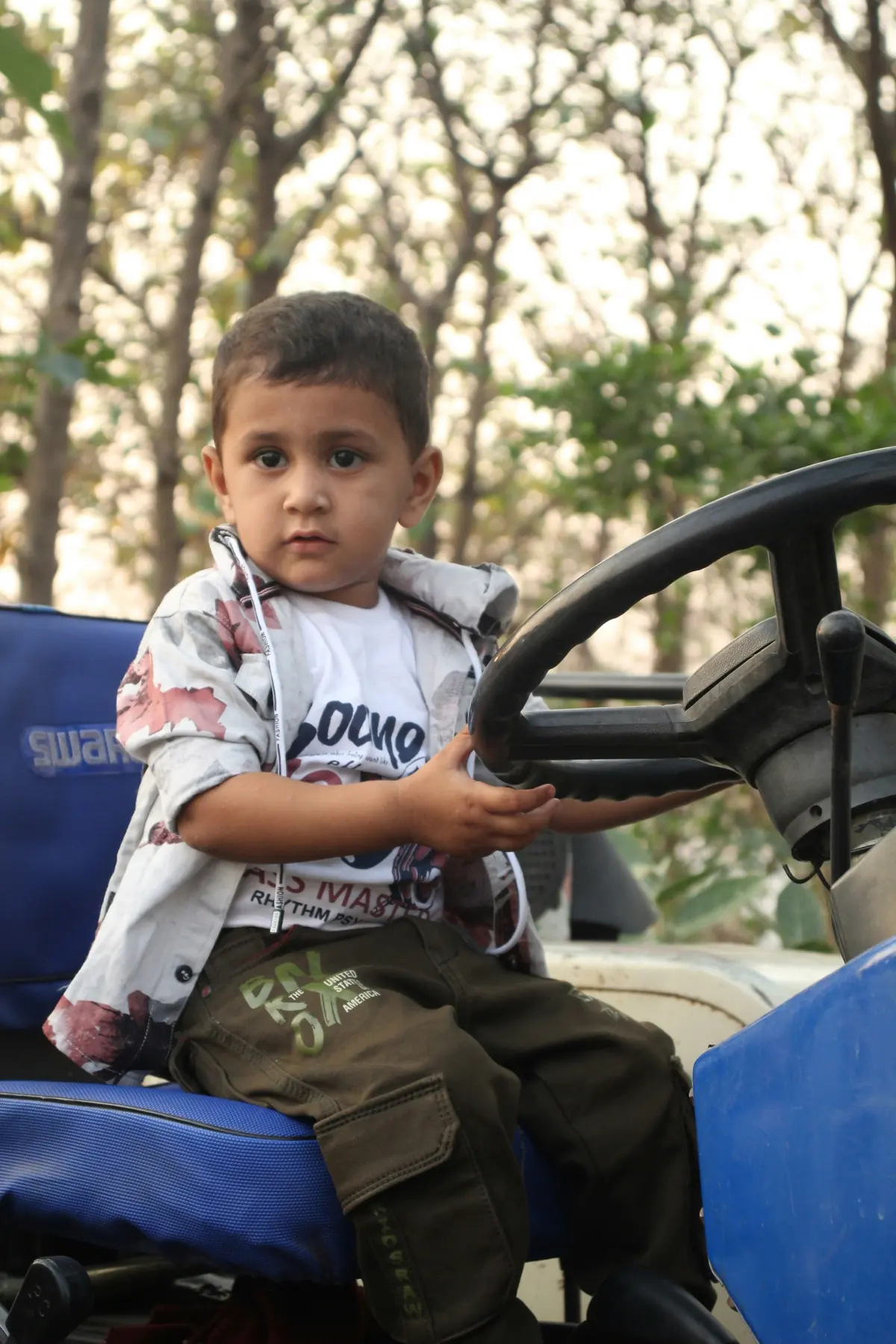 A little boy at the wheel of a tractor on a day out